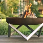modern fire pit with burning wood logs on the patio