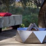 Junda wood-burning stainless steel fire pit on the patio near the bench with red cushions